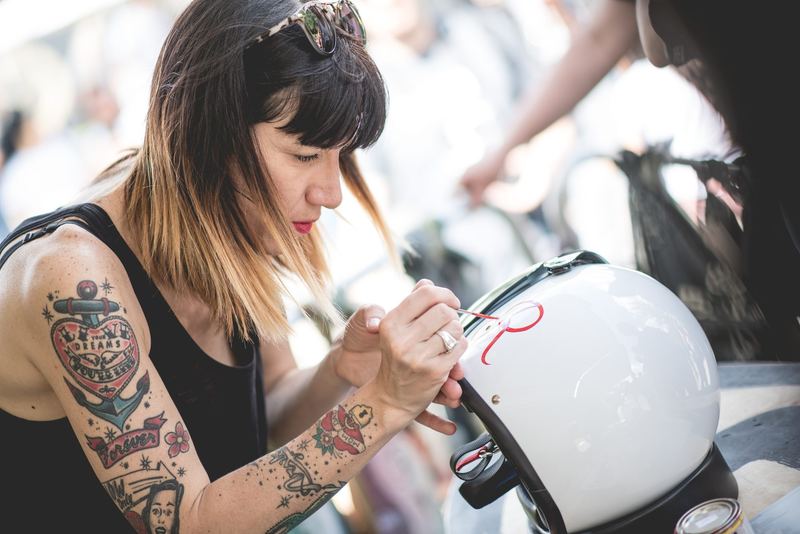 Artista tatuata che dipinge a mano un casco