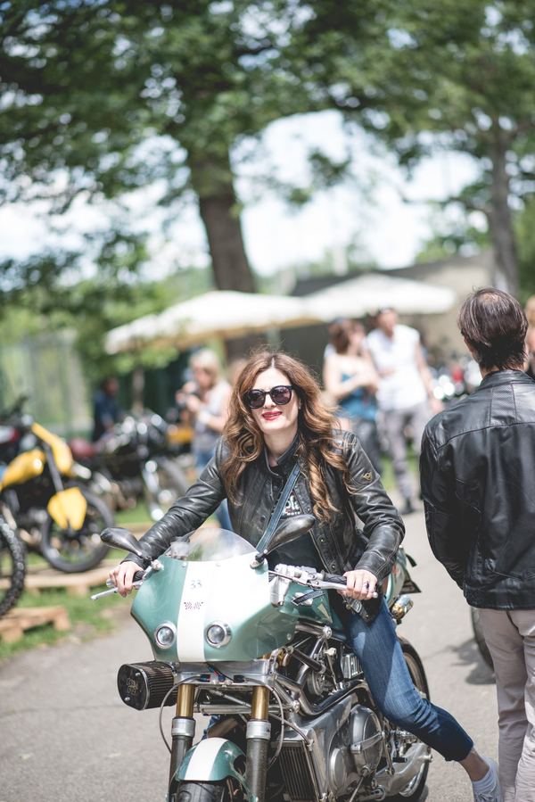 Ragazza sorridente su cafe racer verde