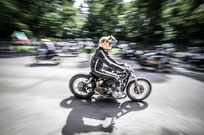 Pilota in giubbotto di pelle su una special d'epoca, lo sfondo mosso dalla velocità