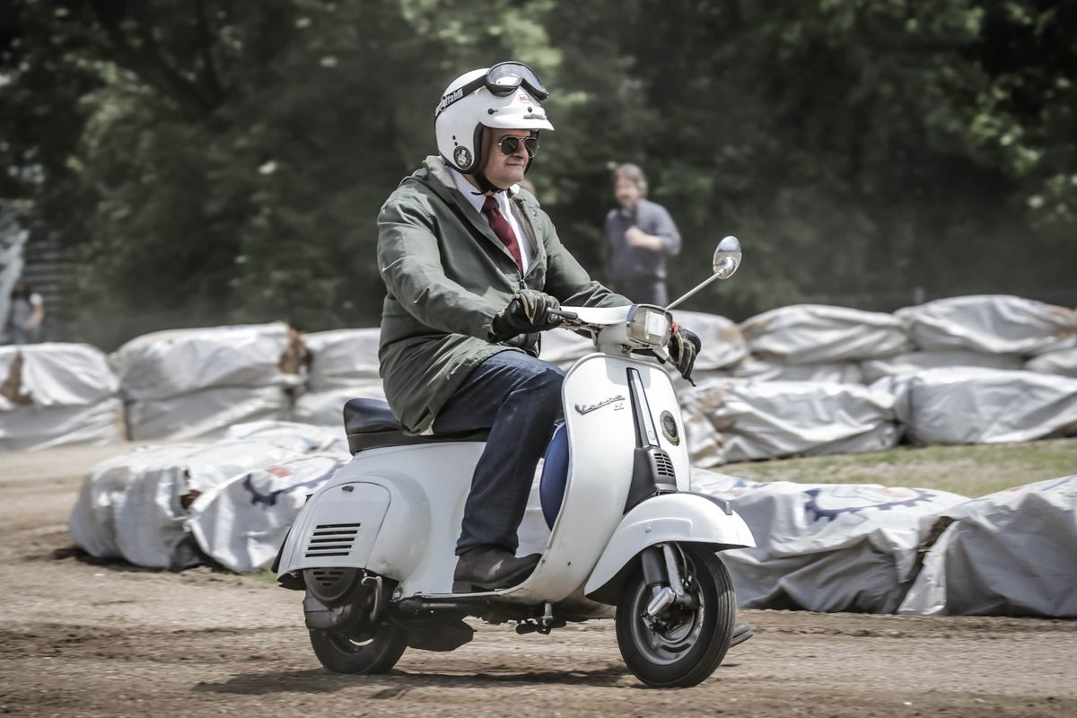 Signore in giacca su una Vespa in mezzo al flat track