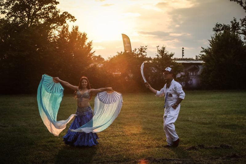 Danzatrice con ali di seta sul prato al tramonto