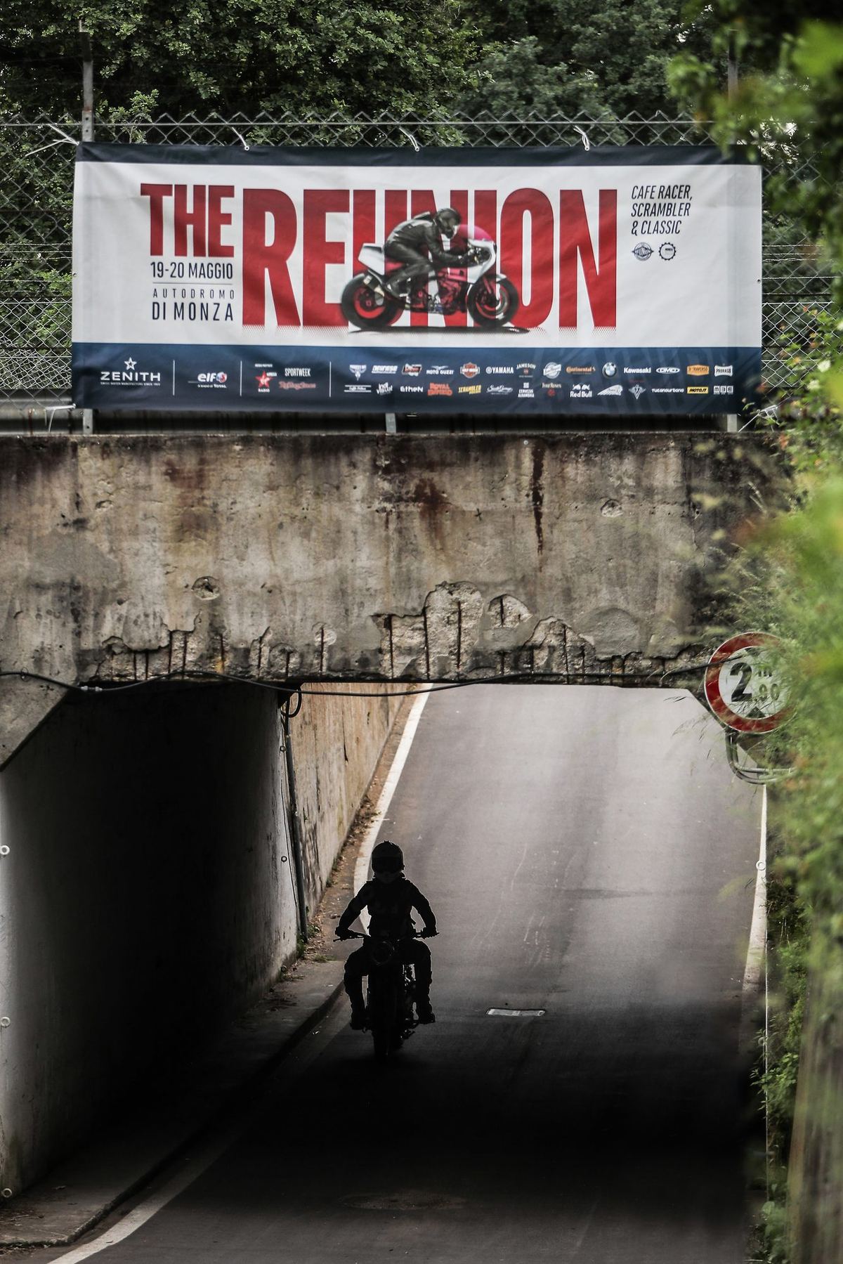 Si entra dal sottopasso sotto lo striscione The Reunion, motociclista in controluce